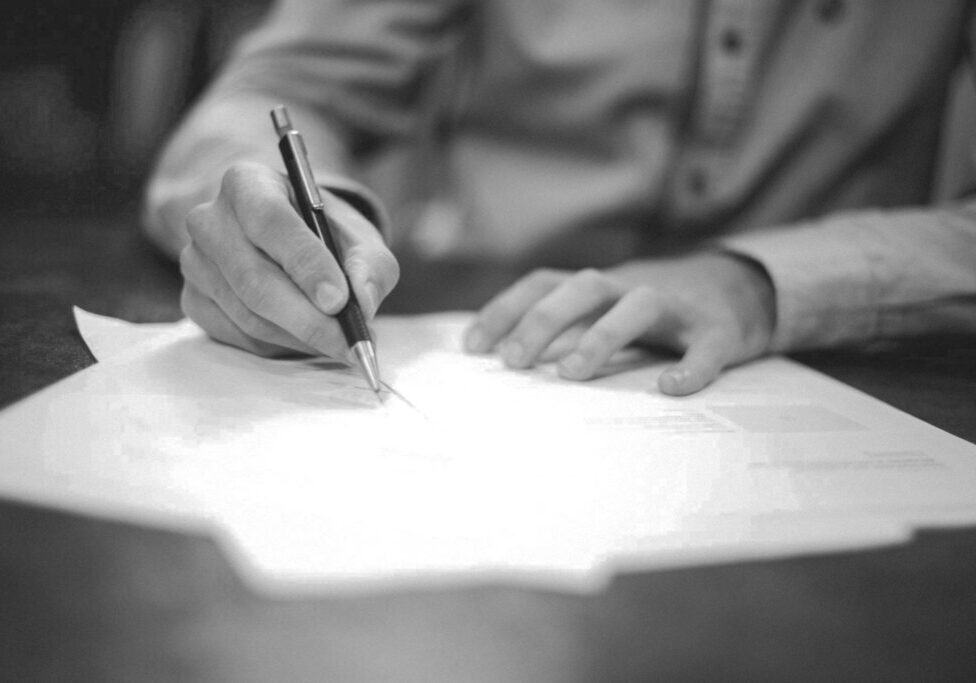 A person writing on paper with a pen.